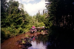 Robert Walsh towing wing on trailer with ATV on the trail from the lake